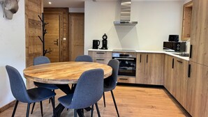 Una cocina moderna con una mesa redonda de madera, sillas azules y armarios de madera.