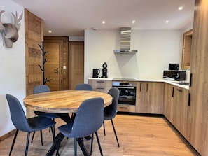Eine moderne Küche mit einem runden Holztisch, blauen Stühlen und Holzschränken.