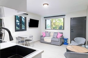 A modern living room with a sofa, a TV, a dining area, and a kitchen. - Entire complex  Beachfront Villa Complex 12 Bedrooms, 6 Baths, Sleeps 48 (Dorado)