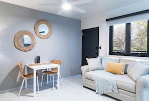 A room with a white table and two wicker chairs, a beige sofa with a throw blanket, two wall-mounted mirrors, and a ceiling fan. - Entire complex  Beachfront Villa Complex 12 Bedrooms, 6 Baths, Sleeps 48 (Dorado)