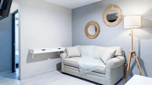 A modern living room with a sofa, two wall-mounted mirrors, a floor lamp, and a white console table.