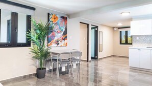 A modern kitchen with white cabinets, a large window, and a potted plant.
