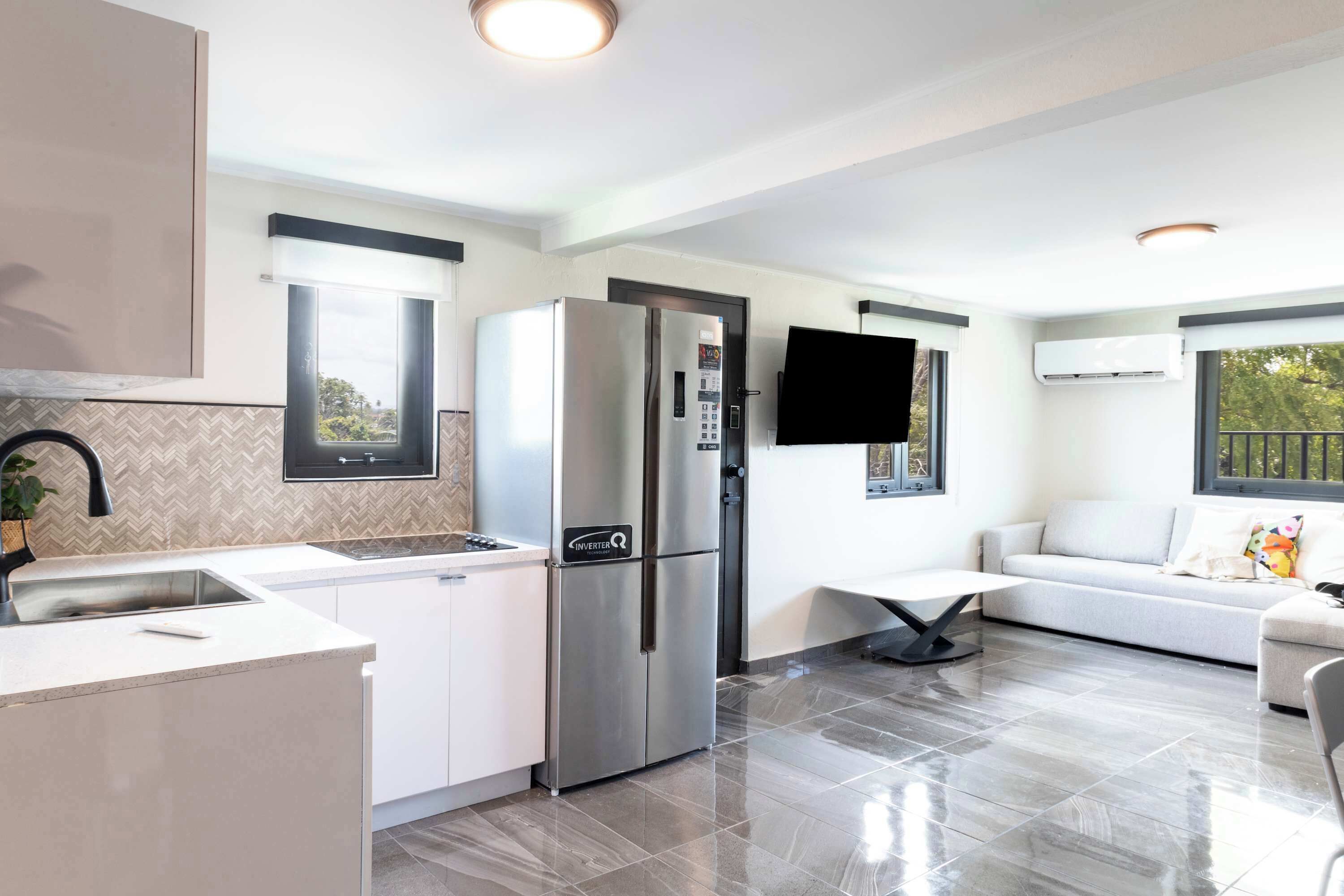 A modern kitchen with a built-in refrigerator, a sink, and a dining area with a table and chairs.
