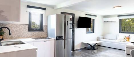 A modern kitchen with a built-in refrigerator, a sink, and a dining area with a table and chairs.