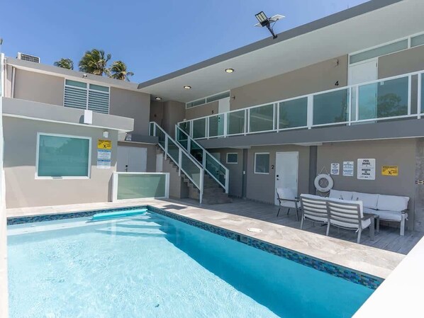 Um hotel moderno com piscina, área de estar ao ar livre e escadaria entre os andares.