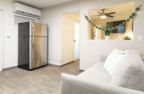 A modern kitchen with a stainless steel refrigerator, a ceiling fan, and a wall-mounted air conditioner. - AQUA Terrazas 1+2+3 · 3-Studio Combo Seaside Suite (Dorado)