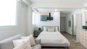 A modern bedroom with a bed, a sofa, a bedside table, a mirror, and a wardrobe. - AQUA Terrazas 1+2+3 · 3-Studio Combo Seaside Suite (Dorado)