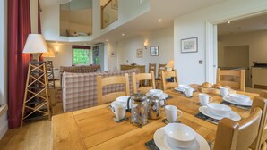 Un coin repas avec une table en bois mise pour le petit-déjeuner, comprenant des tasses, des bols et une cafetière.