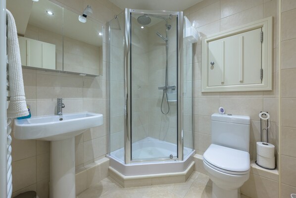 A modern bathroom with a glass-enclosed shower, a pedestal sink, and a toilet.