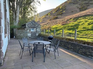 Une terrasse avec un mur en pierre, un bâtiment en pierre et une vue sur une colline.