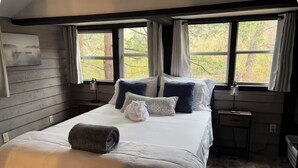 A bedroom with a bed, two bedside tables, a window with curtains, and a painting on the wall. - NEW LISTING:Spring River:Creek Cabin, Private Footage on South Fork Spring River (Hardy)