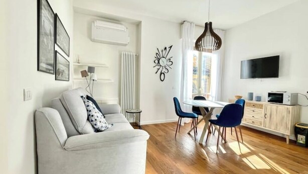 A modern living room with a sofa, dining table, chairs, and a TV.