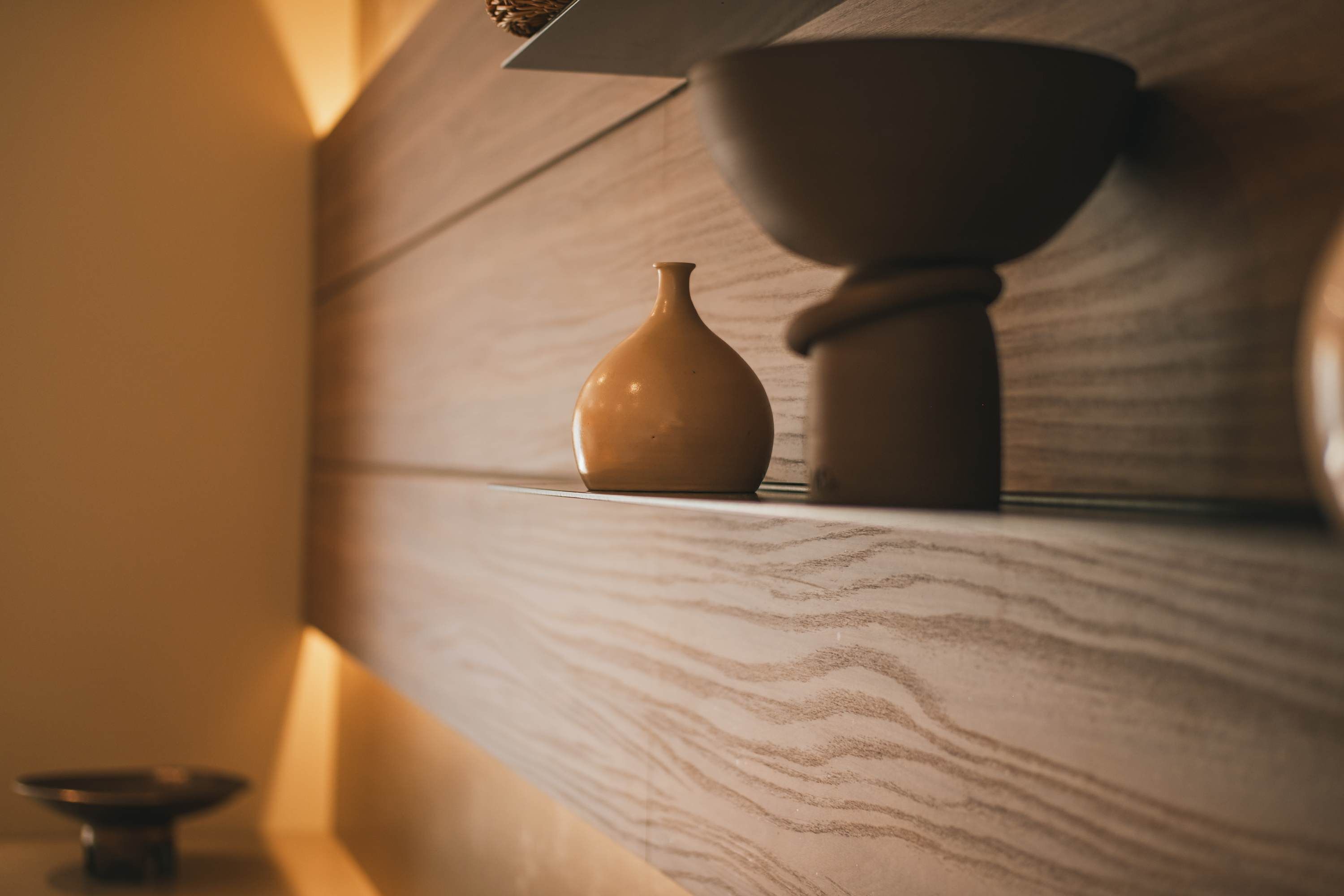 A wooden shelf with a ceramic vase and a bowl.