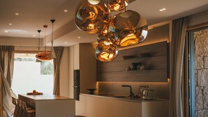 Een moderne keuken met een centraal eiland, hanglampen en een eethoek met stoelen.