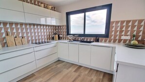 Une cuisine moderne avec des meubles blancs, un plancher en bois et une fenêtre qui laisse entrer la lumière naturelle.