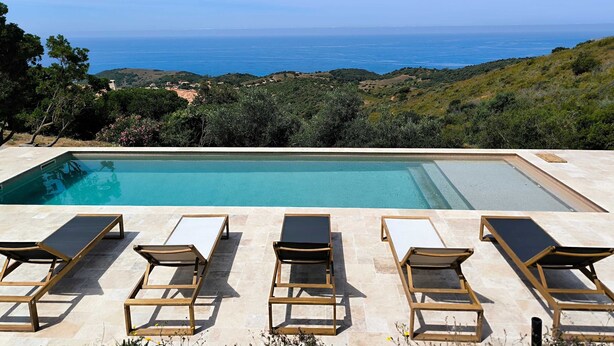 Une piscine avec six chaises longues et vue sur la mer.