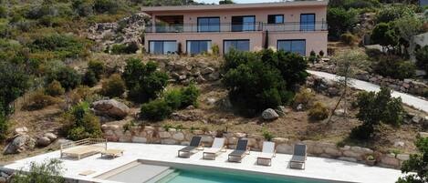 Ein modernes Haus mit Pool, umgeben von natürlicher Landschaft und felsigem Gelände.