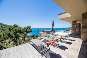A wooden deck with lounge chairs overlooking a coastal view.