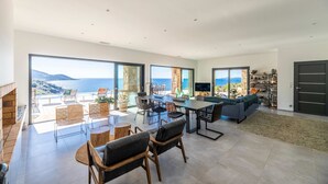 A spacious living area with a large dining table, comfortable seating, and a view of the sea. - Architect Villaproperty Sea View Close to the Beaches (Calcatoggio)