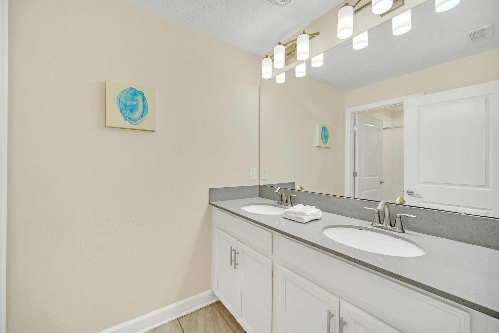 A bathroom with two sinks, a large mirror, and a ceiling light fixture.