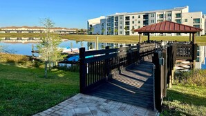 Une terrasse en bois mène à un belvédère d’où l’on a vue sur un lac, avec des immeubles d’habitation modernes en arrière-plan.