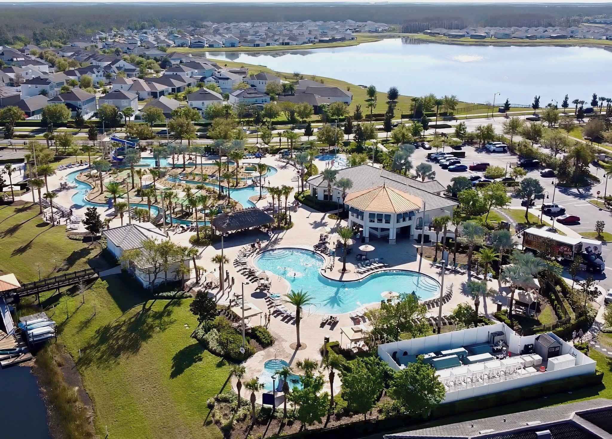 Un resort con varias piscinas, un pabellón central y vista a un lago.
