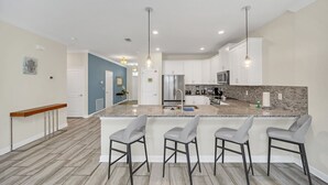 A modern kitchen with a large island, bar stools, and stainless steel appliances. - South Pool | Game Room | Waterpark | Disney 9036 (Four Corners)