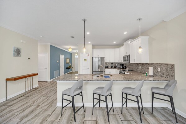 A modern kitchen with a large island, bar stools, and stainless steel appliances. - South Pool | Game Room | Waterpark | Disney 9036 (Four Corners)