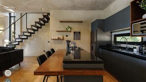 Eine moderne Küche mit einer zentralen Kochinsel, dunklen Schränken und einem Edelstahl-Kühlschrank.