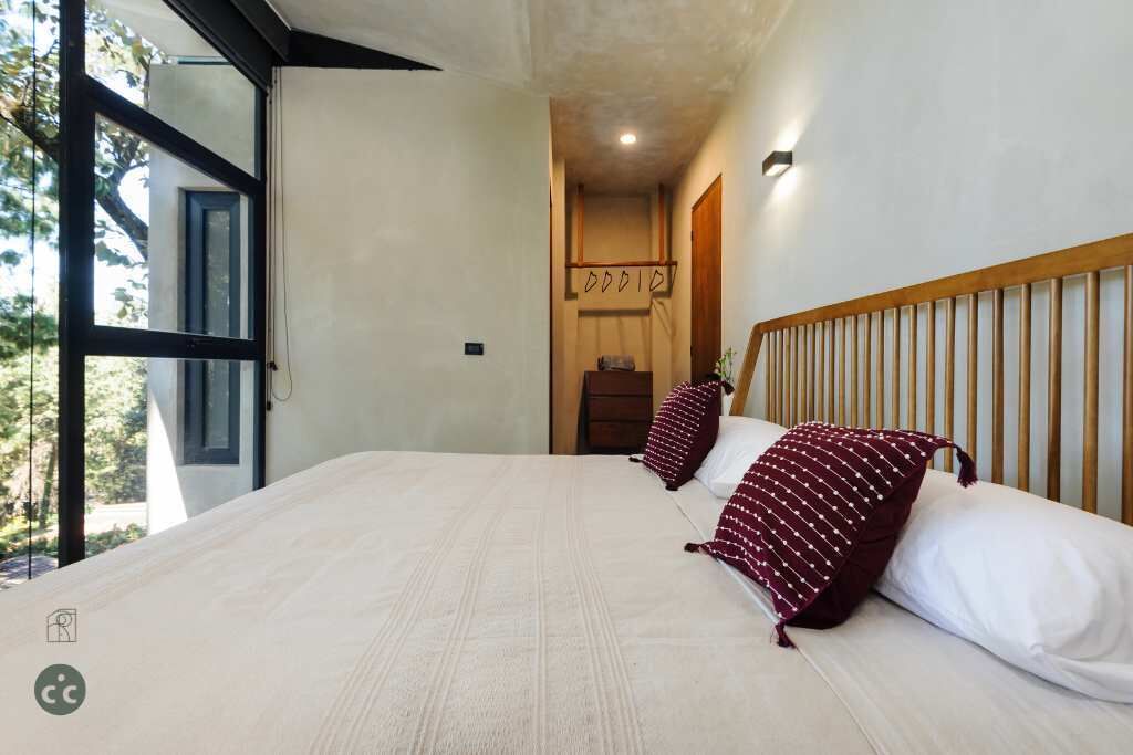 A bedroom with a large bed, a wooden headboard, and a view of the outdoors.