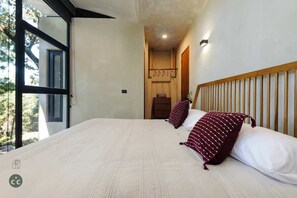 A bedroom with a large bed, a wooden headboard, and a view of the outdoors.