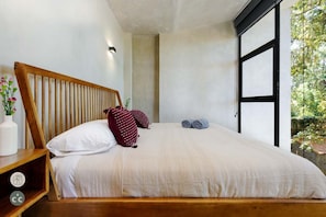 A bedroom with a wooden headboard, a white bedspread, and a nightstand with a clock.