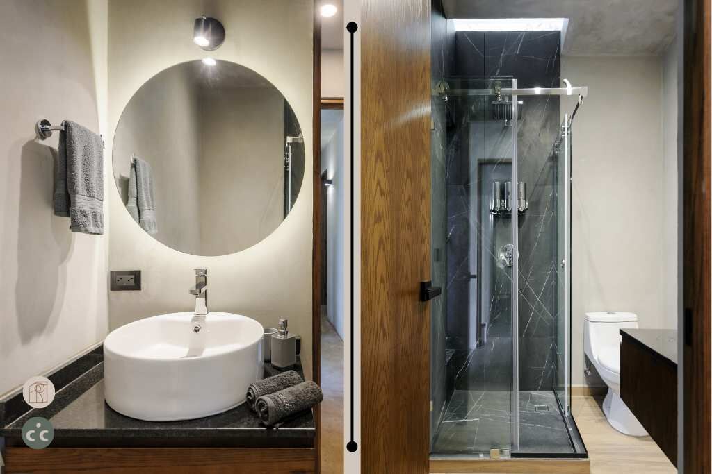 A modern bathroom with a round mirror, a white sink, and a glass-enclosed shower.