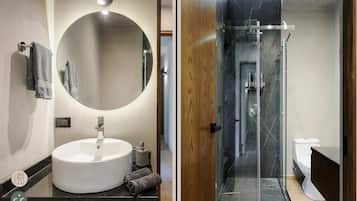 A modern bathroom with a round mirror, a white sink, and a glass-enclosed shower.