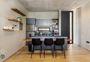 Una cocina moderna con una isla central, taburetes negros y estantes empotrados.