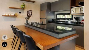 Une cuisine moderne dotée d’un îlot central, de chaises noires et d’appareils électroménagers intégrés.