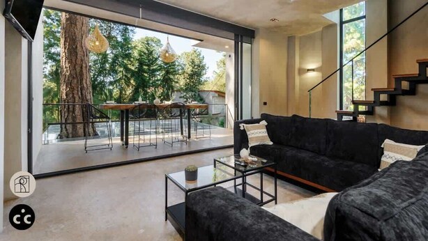 Un salon moderne avec un canapé noir, une table basse en verre et un coin repas comprenant une table et des chaises.