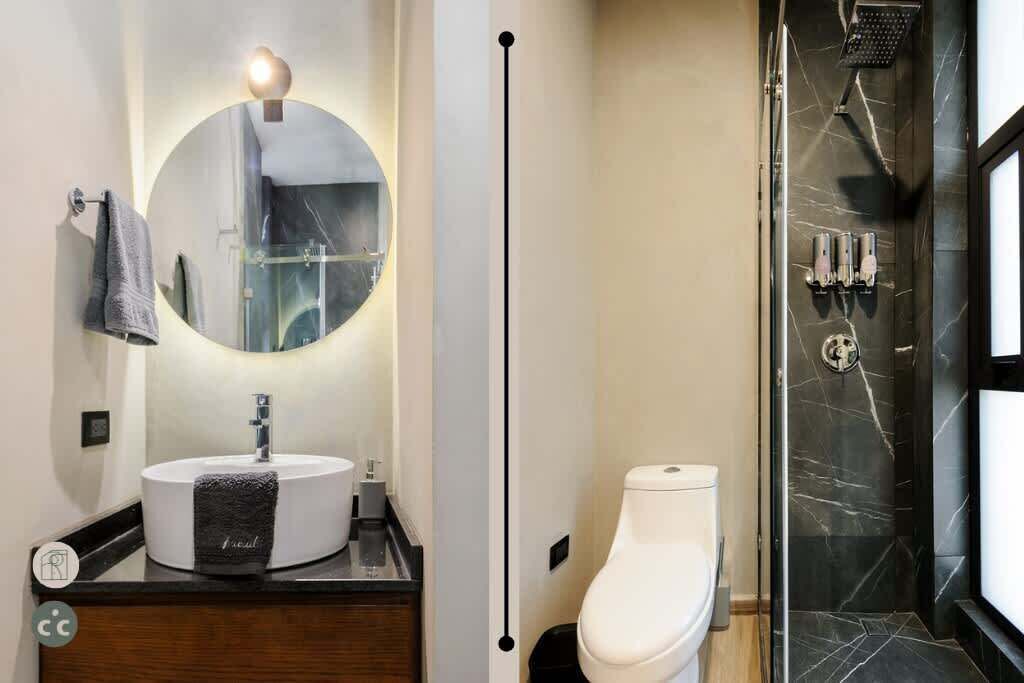 Une salle de bain moderne avec un miroir rond, un lavabo rond, des toilettes et une douche avec un mur en marbre.