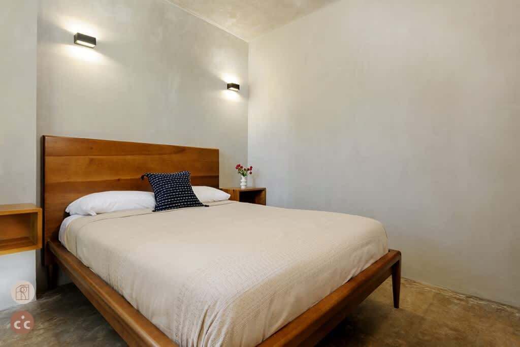 Ein Schlafzimmer mit einem hölzernen Bett, zwei Nachttischen und Wandleuchten.