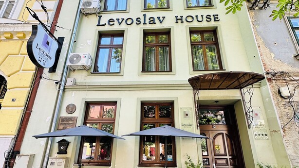 A building with the sign "Levoslav House" and outdoor seating with umbrellas.