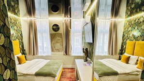 A mirrored room with two beds, a white desk, and a red patterned carpet.