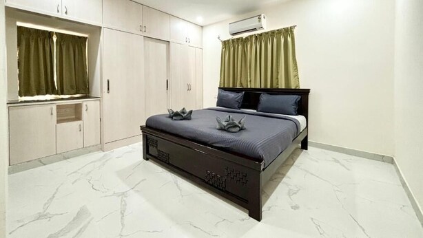 A bedroom with a bed, wardrobe, ceiling fan, air conditioning unit, and curtains. - 3 Bee's Service Apartments (Hyderabad)