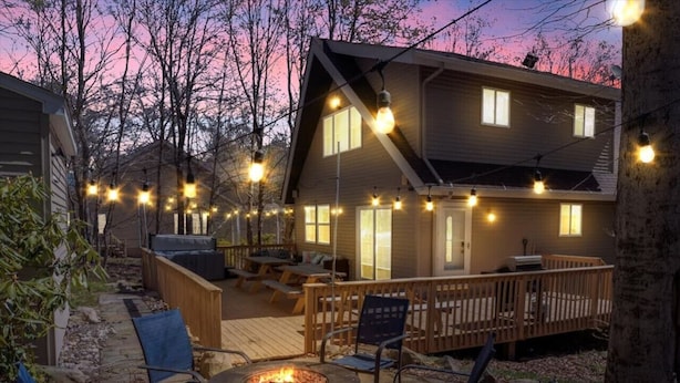 Eine gemütliche Außenpatio mit Feuerstelle, Holzterrasse und Lichterketten.