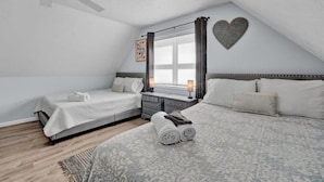 Ein Schlafzimmer mit zwei Betten, einem Deckenventilator, einem Fenster mit Vorhängen und einer herzförmigen Dekoration an der Wand.