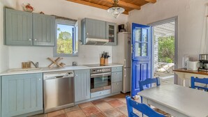A kitchen with blue cabinets, a dishwasher, an oven, and a coffee maker. - Quiet area with Beach access (Chrisi Akti)