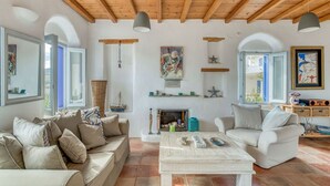 A spacious living room with wooden beams, a fireplace, and modern furnishings. - Quiet area with Beach access (Chrisi Akti)