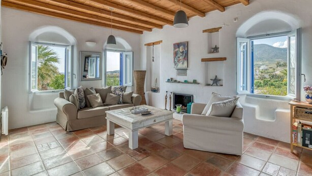 A spacious living room with a high wooden ceiling, large arched windows, a fireplace, and a view of the landscape. - Quiet area with Beach access (Chrisi Akti)