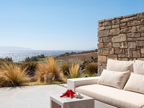 A stone wall, a white sofa with cushions, and a view of the sea. - Villa Ena - Beach getaway (Paros)