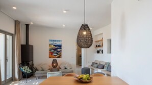 Una sala de estar moderna con una mesa de comedor, sillas, una lámpara colgante y una chimenea.