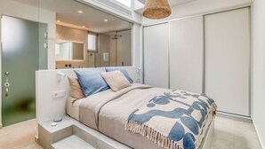 A modern bedroom with a bed, a bedside table, a hanging light fixture, and a wardrobe. - Spick & span in Paros island (Aspro Chorio)